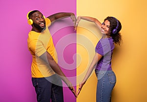 Couple with headset listen to music and make the shape of heart with arms. violet and yellow background