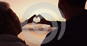 Couple, heart and hands at beach in sunset for love, care and romantic holiday, vacation and date from the back. Man