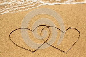 Couple of hearts drawn on the beach sand in sunny day. Love.