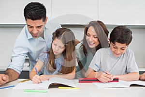 Couple helping kids with their homework in kitchen