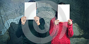 Composite image of couple hiding faces with blank papers