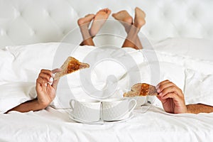 Couple Hiding Under Duvet Enjoying Breakfast In Bed