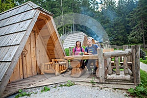 Couple hiker posing outside a wooden hut at a glamping site at Lake Bloke, Nova Vas, Slovenia