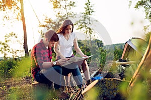 Couple hikers in the mountains, they is looking at map