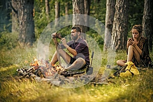 Couple of hikers relax at bonfire in forest