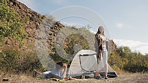 Couple of hikers resting near the tent in the warm sunshine