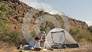 Couple of hikers resting near the tent in the warm sunshine