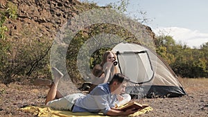 Couple of hikers resting near the tent in the warm sunshine