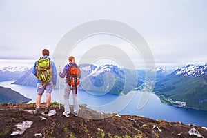 Couple of hikers on top of the mountain, group of backpackers traveling in Norway fjords