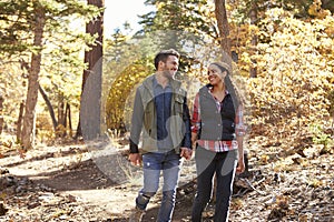 Couple hiking in a forest hold hands and look at each other