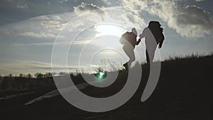 Couple hiking help each other silhouette in mountains. Teamwork couple hiking, help each other, trust assistance, sunset