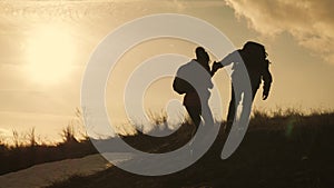 Couple hiking help each other silhouette in mountains. Teamwork couple hiking, help each other, trust assistance, sunset