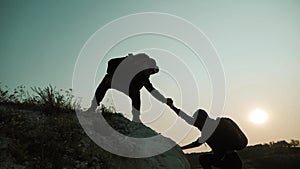 Couple hiking help each other silhouette in mountains. Teamwork couple hiking, help each other, trust assistance, sunset