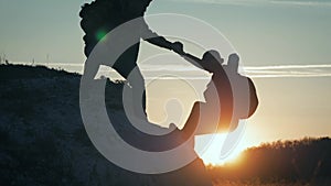 Couple hiking help each other silhouette in mountains. Teamwork couple hiking, help each other, trust assistance, sunset