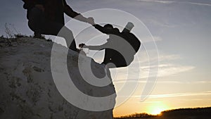 Couple hiking help each other silhouette in mountains. Teamwork couple hiking, help each other, trust assistance, sunset