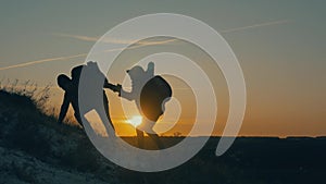 Couple hiking help each other silhouette in mountains. Teamwork couple hiking, help each other, trust assistance, sunset