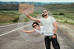 A couple hitchhiking. A man and a woman catch a car by the road. A young couple votes on the road.
