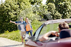 Couple hitchhiking and stopping car on countryside