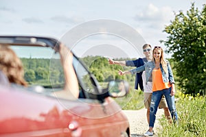 Couple hitchhiking and stopping car on countryside
