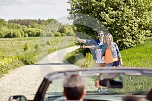 Couple hitchhiking and stopping car on countryside