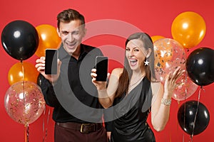 Couple hold in hand cellphone with blank screen celebrating birthday holiday party on red background air