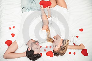 Couple holding big heart in the bed