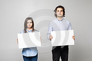 Young couple holding a blank isolated over a white background
