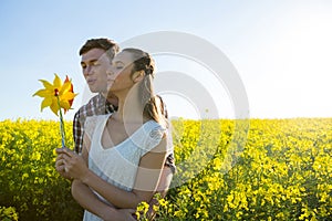 Couple holding blowing pinwheel in mustard field