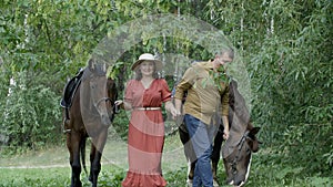 Couple holding bridles and walking with beautiful horses