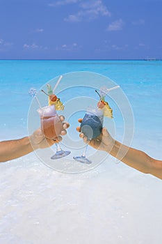 Couple holding cocktail in tropical beach maldives