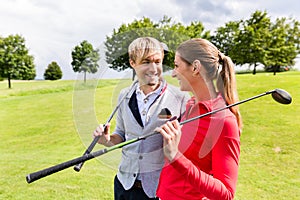 Couple holding golf club looking at each other