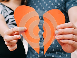Couple holding a half heart shape breaking apart - divorce, split concept