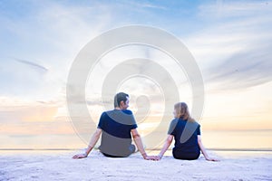 A couple holding hand and seeing each other on the beach with blue sky background