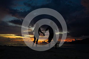 Couple holding hands on the beach with a beautiful sunset in background