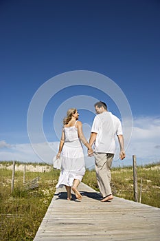 Couple holding hands on beach path.