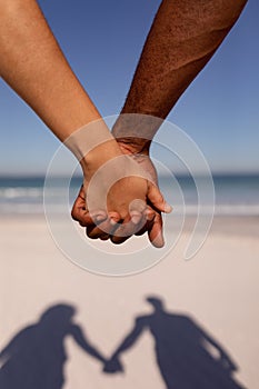 Couple holding hands on beach in the sunshine