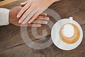 Couple holding hands beside cappuccino