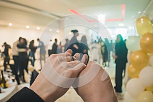 Couple holding hands heading to the dance floor of a party, with lights in the background