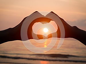 Couple holding hands heart love at sunset on beach