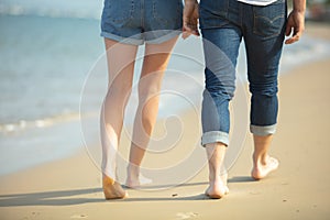 couple holding hands leaving footprints on beach