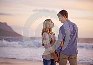 Couple, holding hands and love in looking by water, ocean waves and peace for romance in relationship. People, beach and