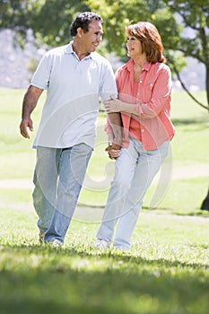 Couple holding hands outdoors by lake smiling