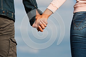 Couple holding hands over blue sky background