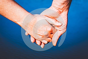 couple holding hands over blue water background