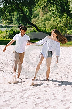 couple holding hands and playing with sand