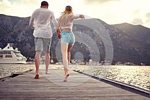 Couple holding hands and run to jump in the water