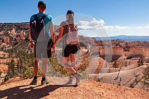 Couple holding hands with scenic aerial view from Fairyland hiking trail on massive hoodoo sandstone rock formations