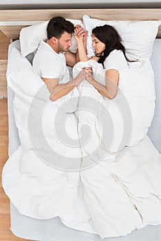 Couple holding hands sleeping on bed