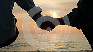 Couple holding hands together. Women holding hands relaxing and walking down the beach at sunrise