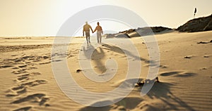 Couple, holding hands and walking on beach, sunset and bonding together on vacation at sea. Back, people and partnership